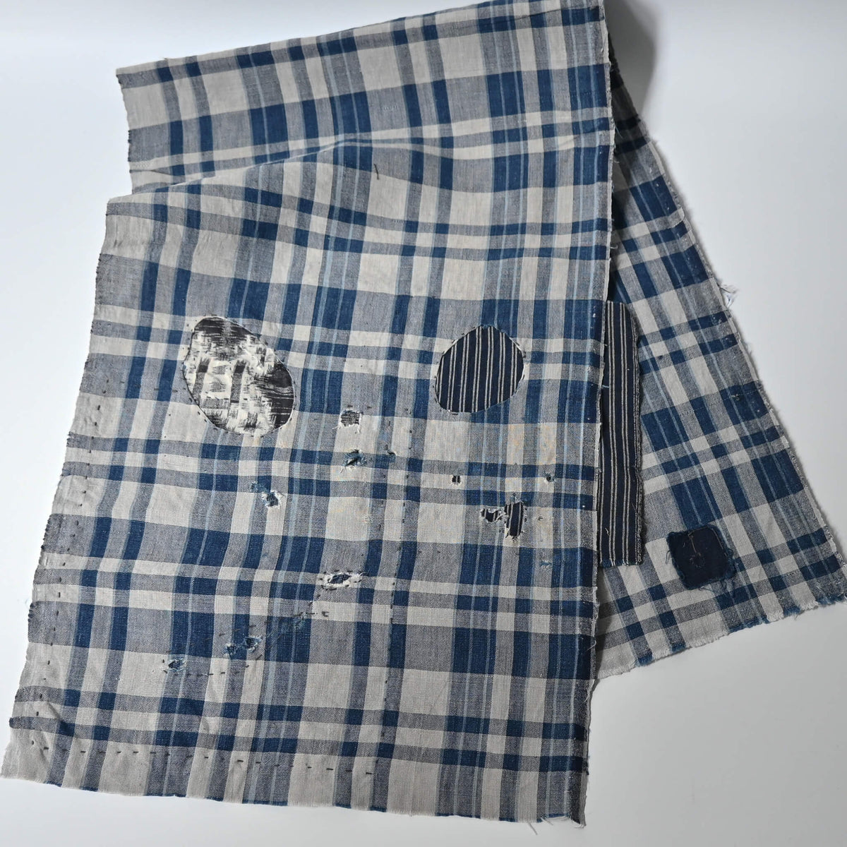 Vintage indigo check cotton with old hand-mended area and contrasting repair fabric.
