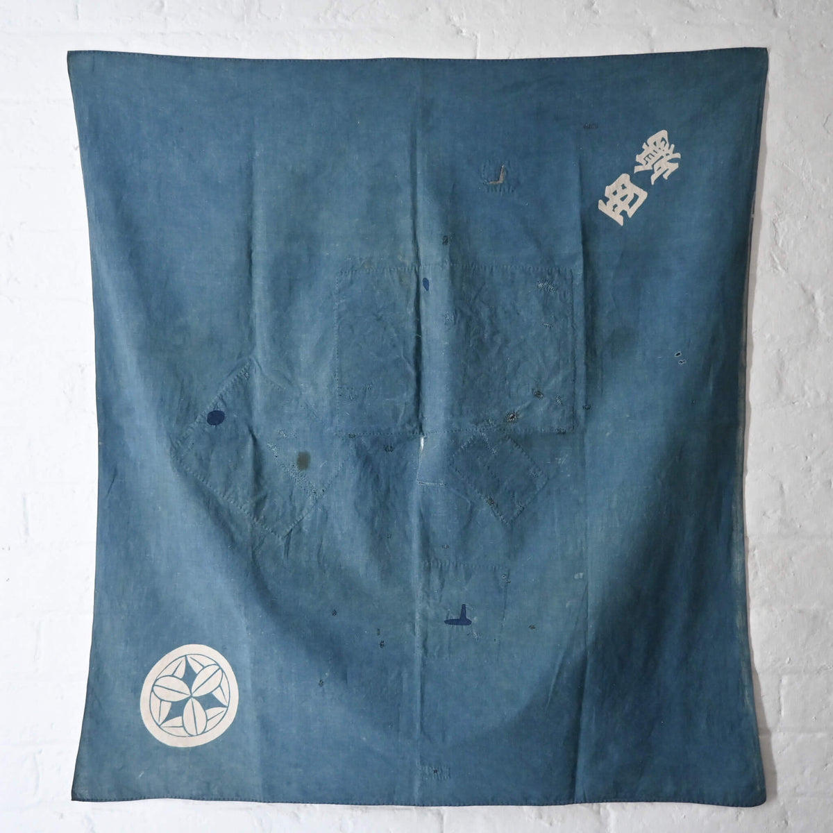 Vintage Japanese indigo cotton furoshiki with various hand-stitched mends, family crest and surname are dyed at corners.