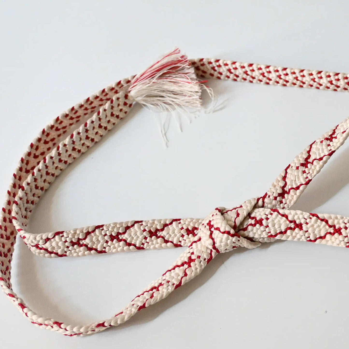 Vintage Kumihimo braided silk Obijime kimono dress accessory, white and red, tied in a knot.