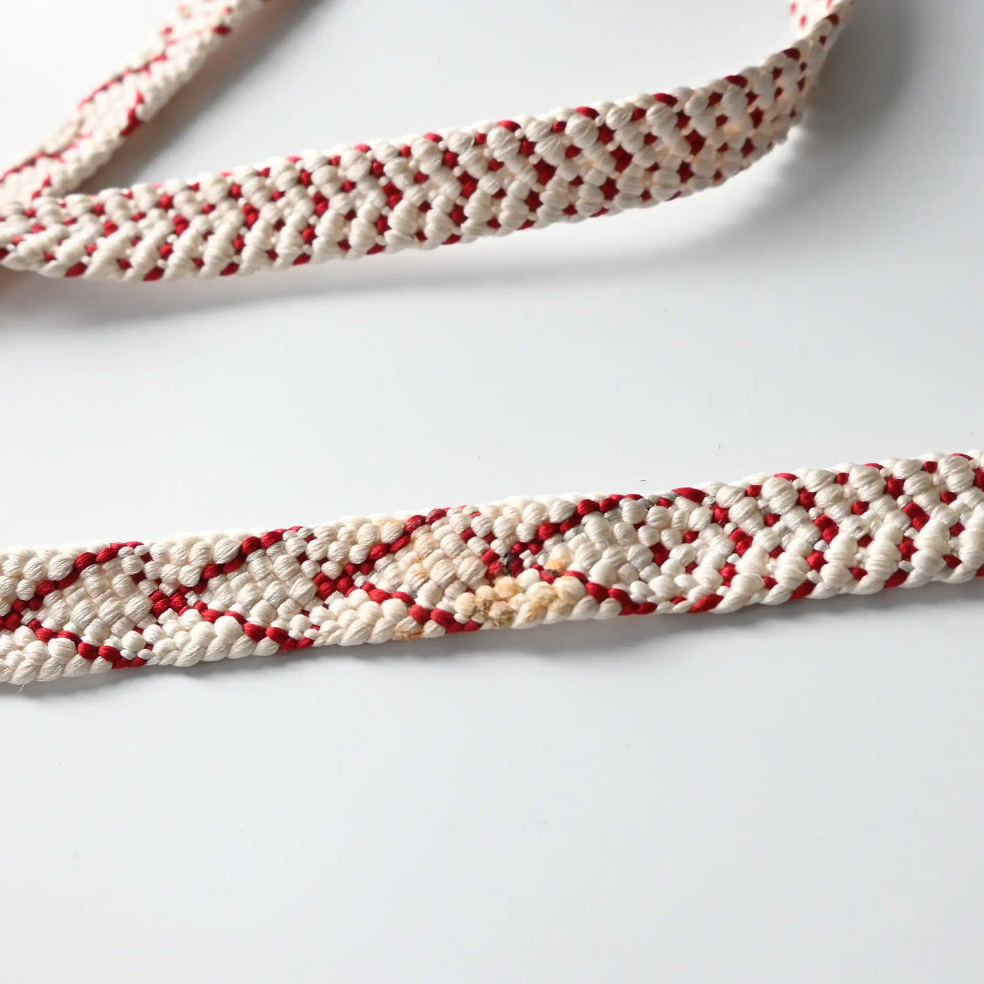 Stained part of vintage Kumihimo braided silk Obijime kimono dress accessory, white and red.
