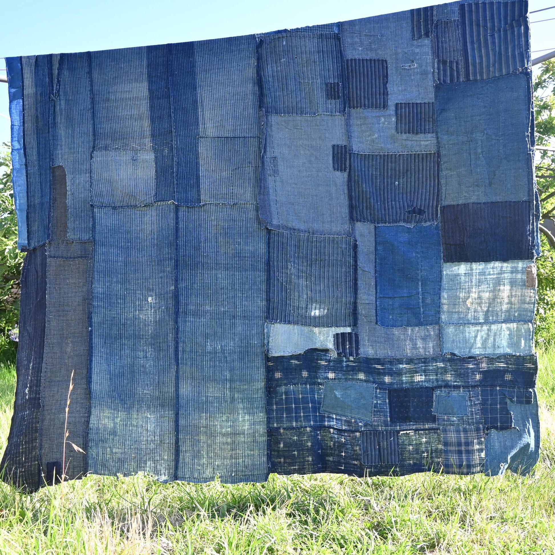 Vintage old Japanese Boro indigo cotton futon cover hanging in the garden.