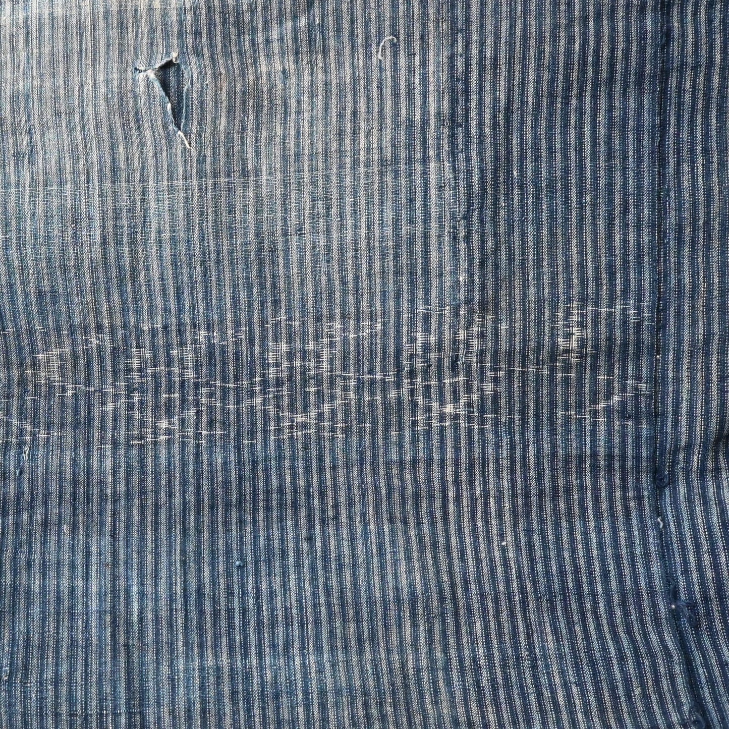 Vintage indigo stripe and Kasuri patterned cotton with a hole.