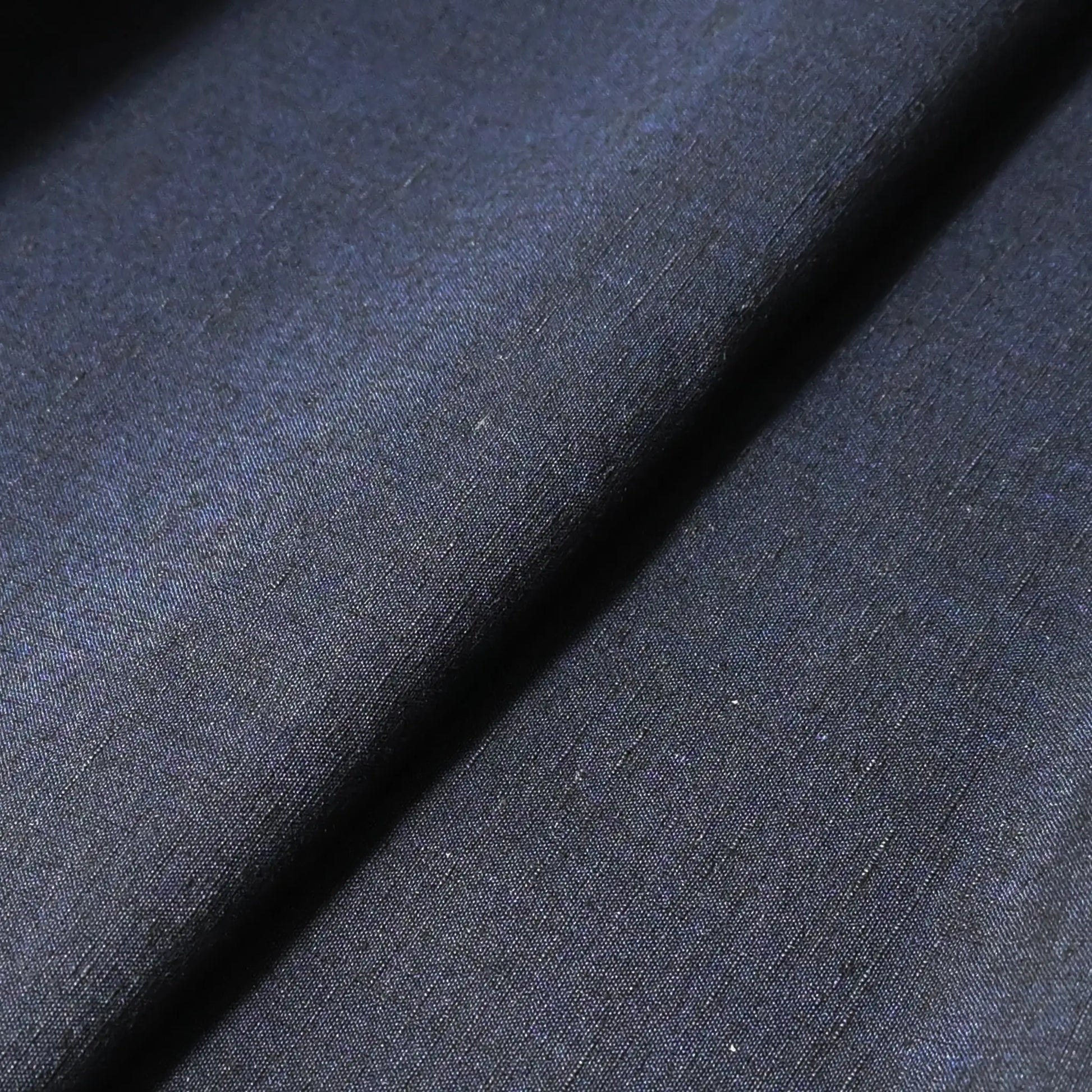 Close-up view of vintage dead stock men's tsumugi silk kimono fabric roll in navy blue.