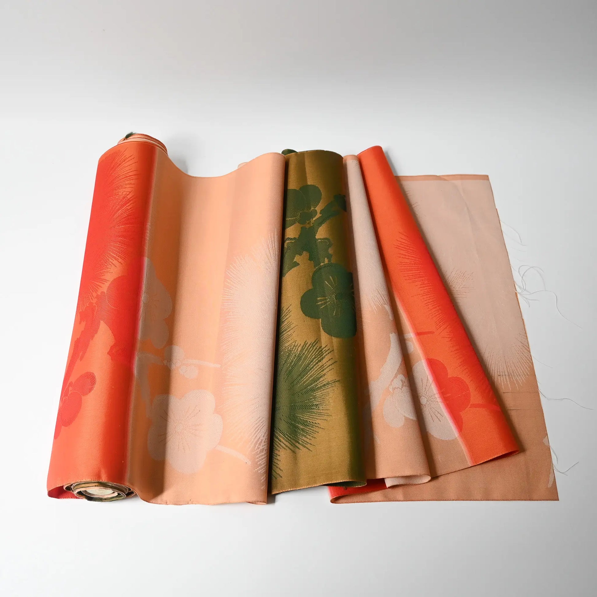 Vintage Japanese silk fabric roll with plum blossom and pine tree in striking orange and green.
