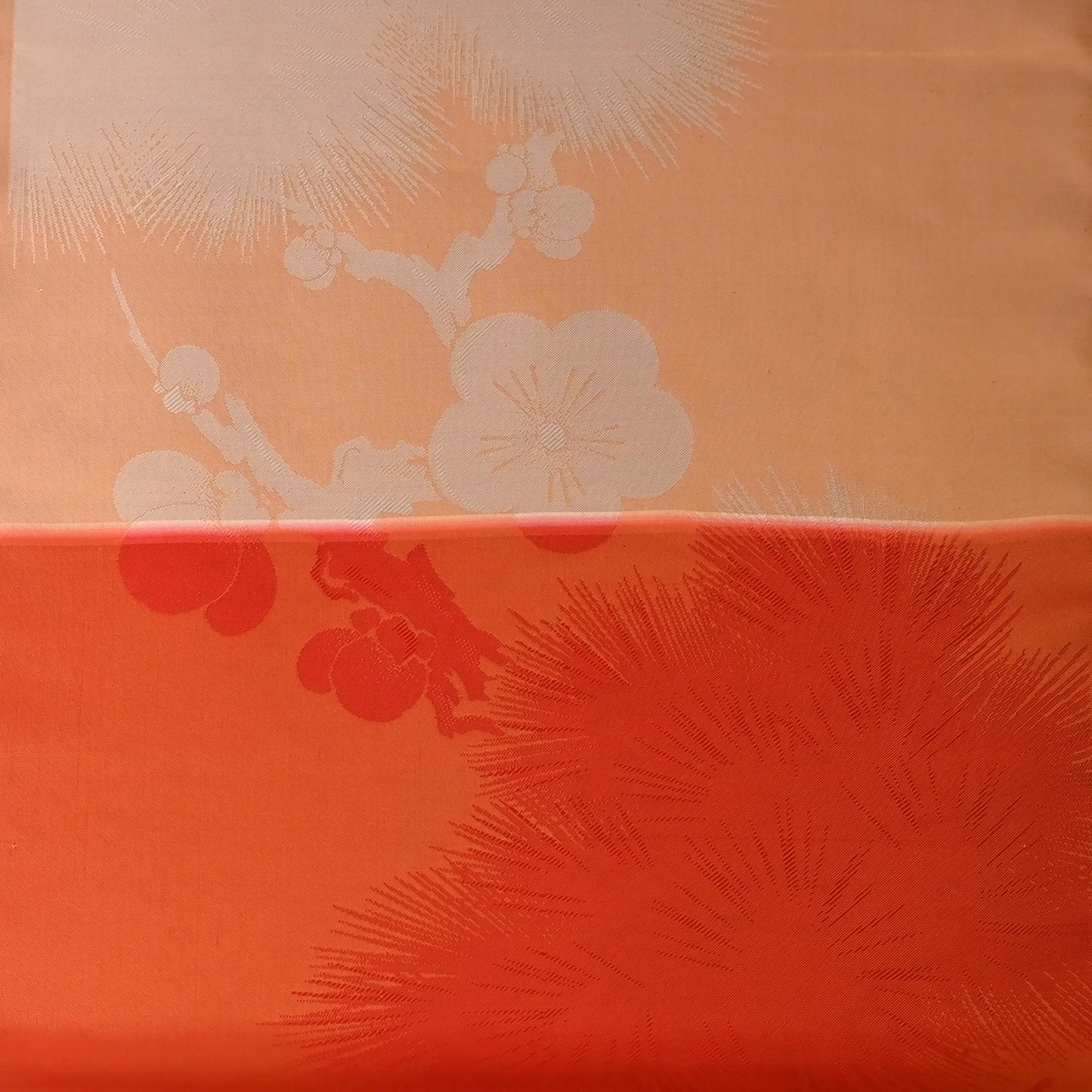Detailed view of vintage Japanese silk fabric with plum blossom in striking orange.