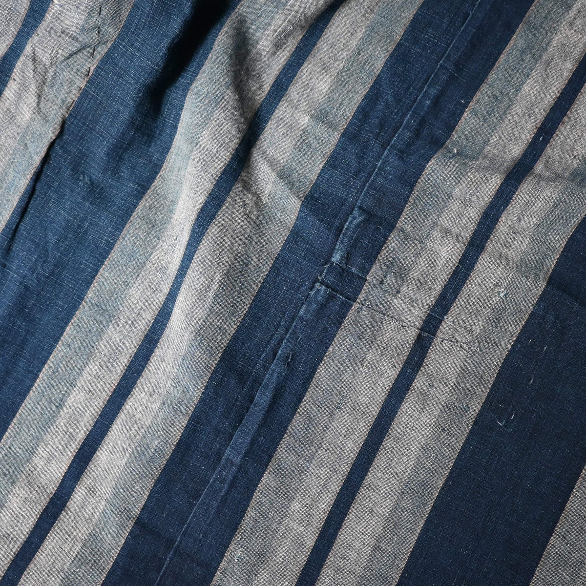 Close-up view of vintage Japanese indigo stripe futon cover with old mends and patches, suitable for boro and patchwork projects