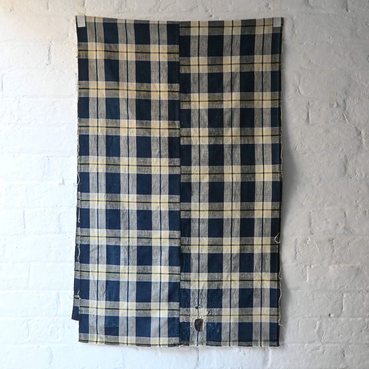 Full view of vintage Japanese indigo and soft yellow check cotton futon cover panel with mended patches.