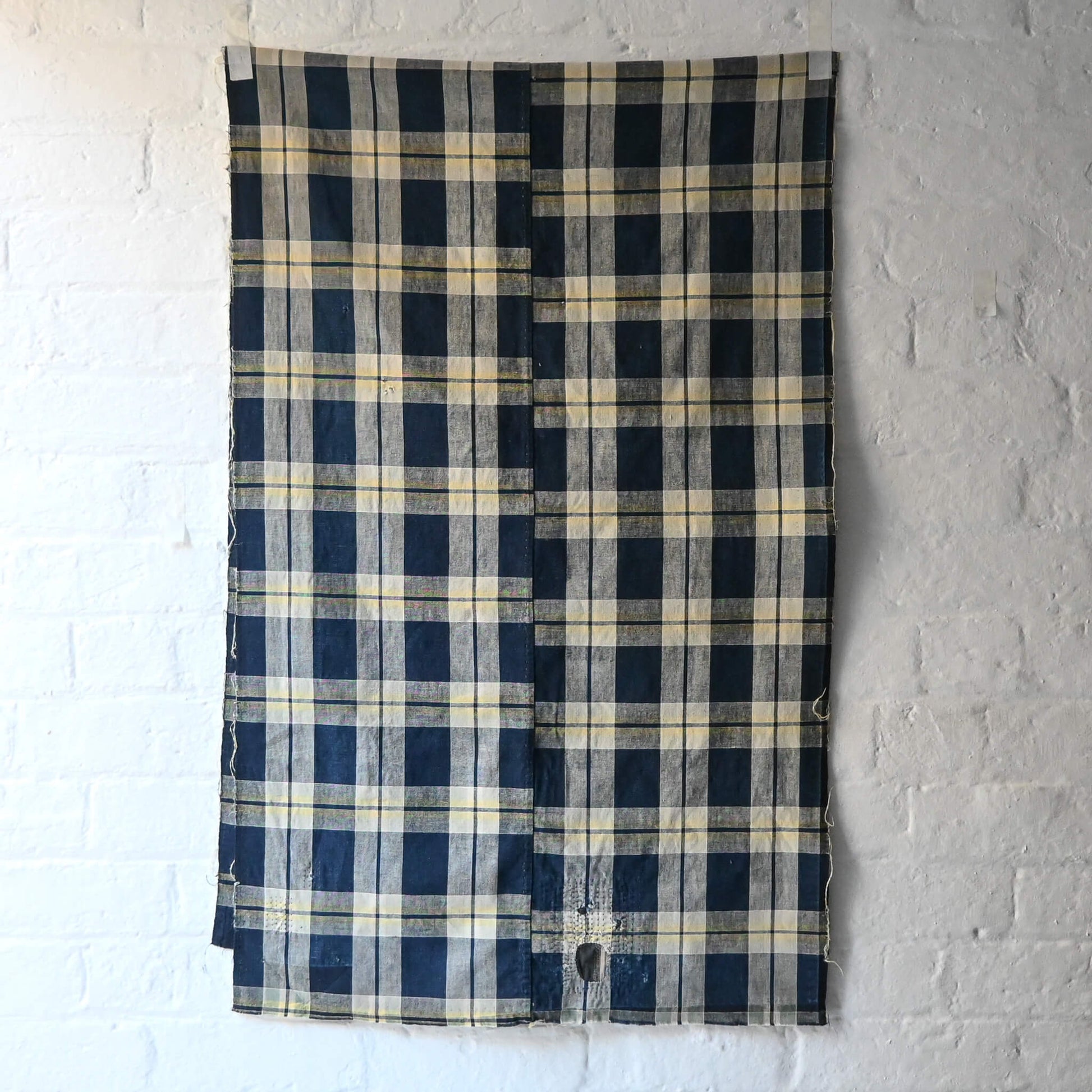 Full view of vintage Japanese indigo and soft yellow check cotton futon cover panel with mended patches.