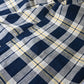 Detailed view of vintage Japanese indigo and soft yellow check cotton futon cover panel with mended patches.