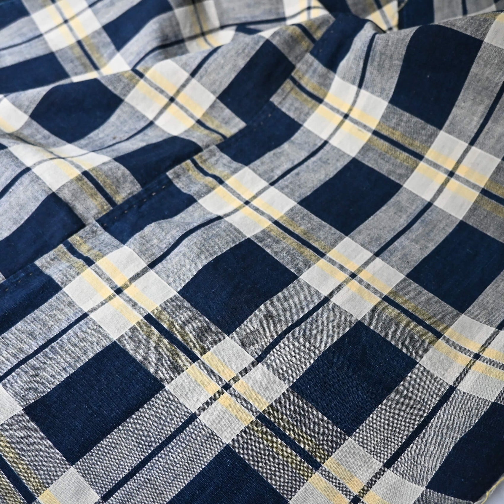 Detailed view of vintage Japanese indigo and soft yellow check cotton futon cover panel with mended patches.