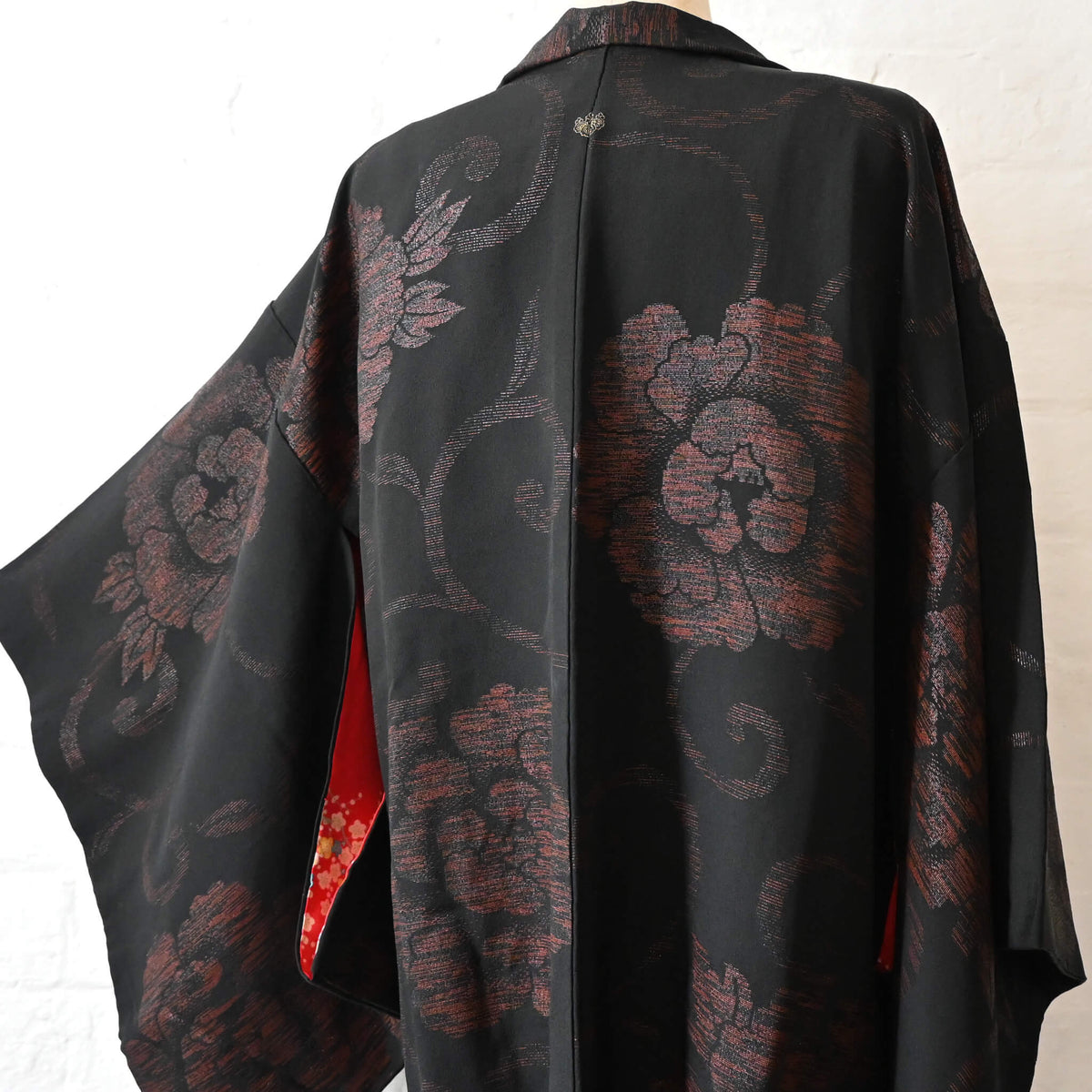 The back bodice of vintage women's black silk crepe haori with woven peony pattern created with lacquer-coated threads.