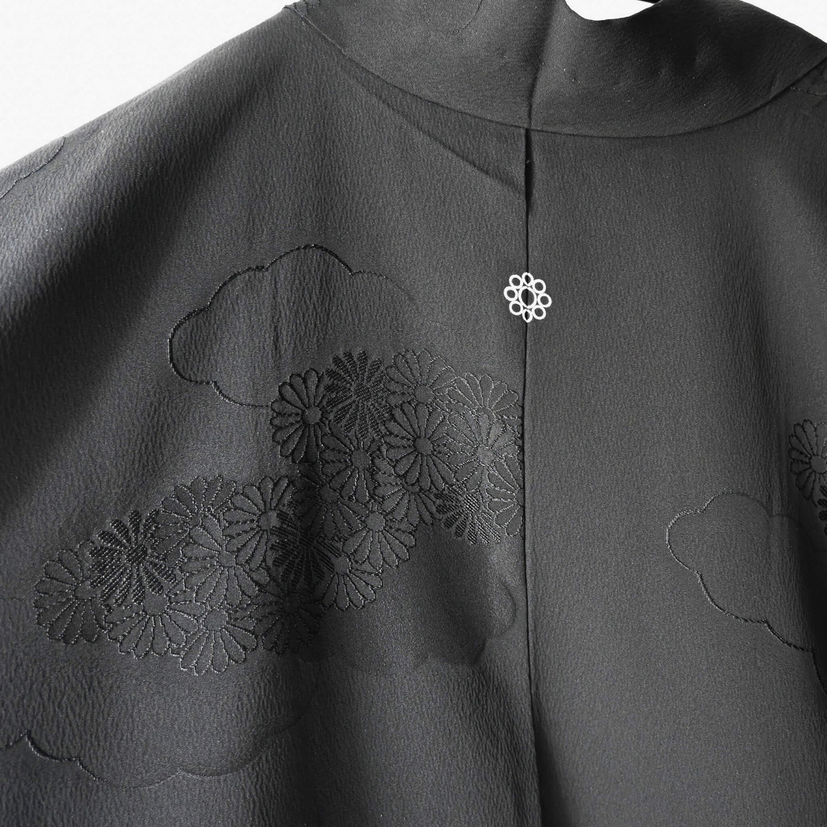 Close-up view of vintage Japanese women's silk haori with black-on-black jacquard chrysanthemum pattern.