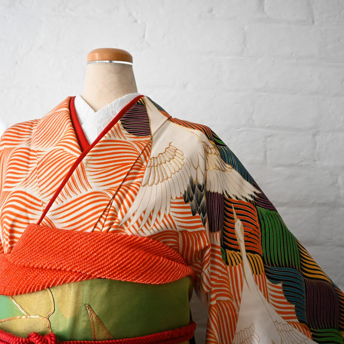 Detailed view of vintage Japanese women's long-sleeved formal kimono Furisode with crane and wave in orange base colour.
