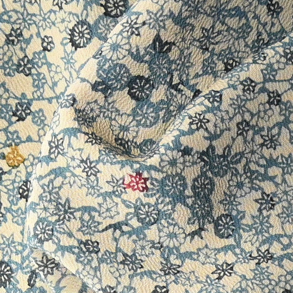Detailed view of vintage katazome stencil dyed silk crepe kimono fabric with small floral pattern, including plum blossoms and chrysanthemums.