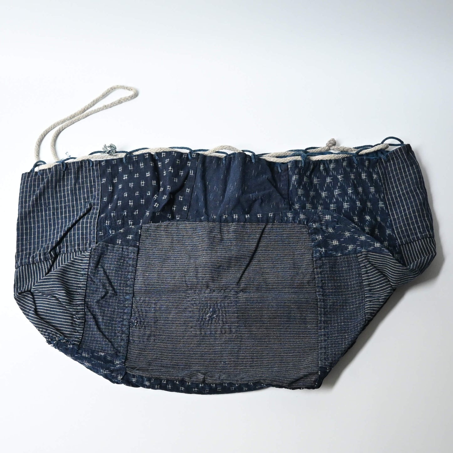 A rare vintage Japanese komebukuro, a traditional drawstring cotton rice bag hand pieced from a variety of indigo cottons.
