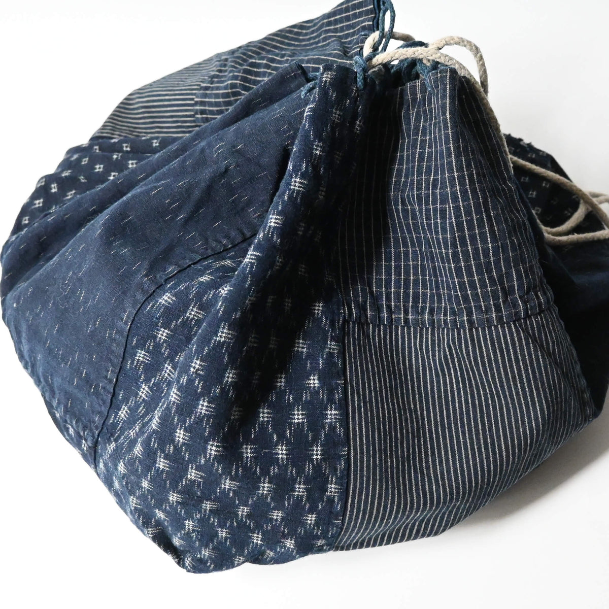 Close-up view of a rare vintage Japanese komebukuro, a traditional drawstring cotton rice bag hand pieced from a variety of indigo cottons.