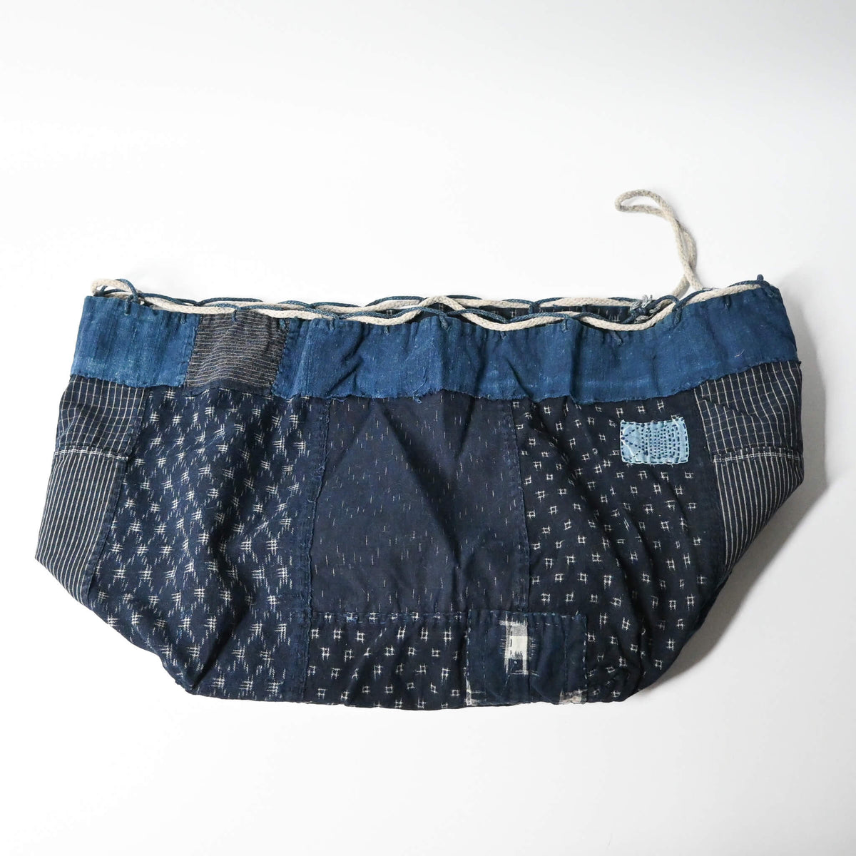 Inside of a rare vintage Japanese komebukuro, a traditional drawstring cotton rice bag hand pieced from a variety of indigo cottons with mended patches.