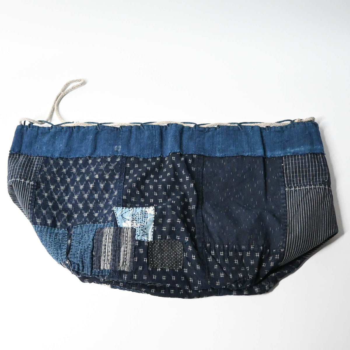 Inside of a rare vintage Japanese komebukuro, a traditional drawstring cotton rice bag hand pieced from a variety of indigo cottons with mended patches.