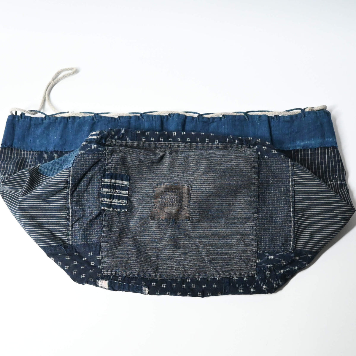 Inside of a rare vintage Japanese komebukuro, a traditional drawstring cotton rice bag hand pieced from a variety of indigo cottons with mended patches.