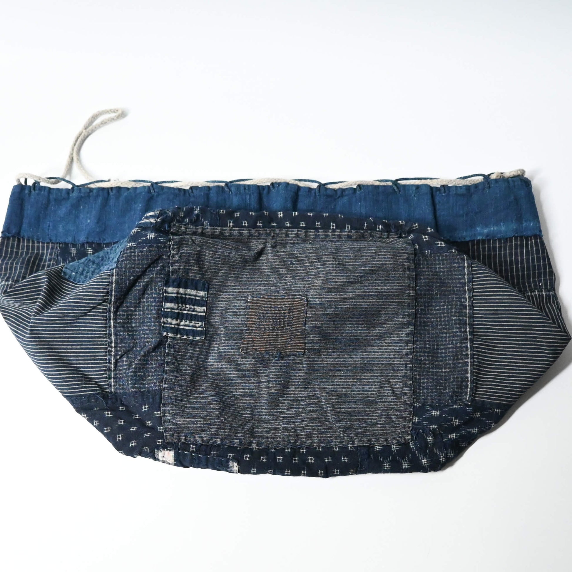 Inside of a rare vintage Japanese komebukuro, a traditional drawstring cotton rice bag hand pieced from a variety of indigo cottons with mended patches.