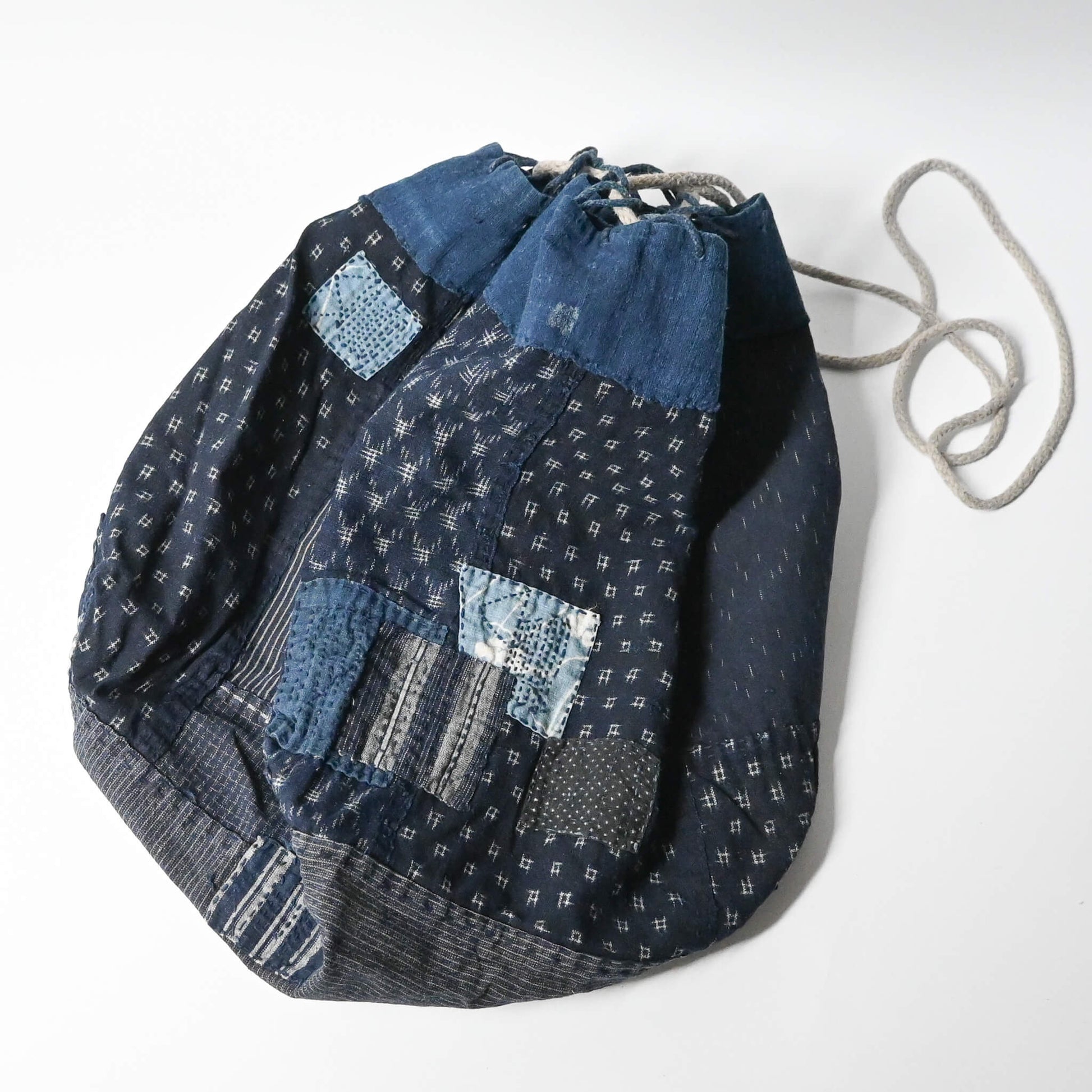 Inside of a rare vintage Japanese komebukuro, a traditional drawstring cotton rice bag hand pieced from a variety of indigo cottons with mended patches.
