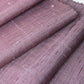 Close-up view of vintage lilac tsumugi silk kimono fabric roll with textured slubs.