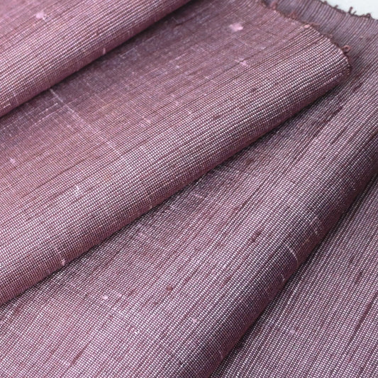 Close-up view of vintage lilac tsumugi silk kimono fabric roll with textured slubs.