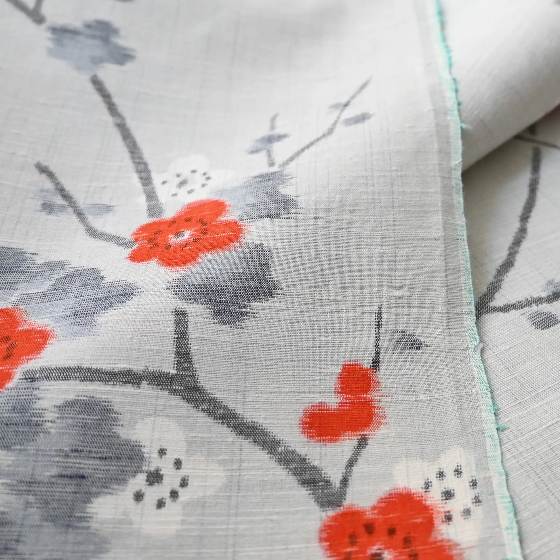 Detailed view of vintage Japanese tsumugi silk kimono fabric piece in light grey with charming plum blossom design.