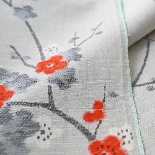 Detailed view of vintage Japanese tsumugi silk kimono fabric piece in light grey with charming plum blossom design.