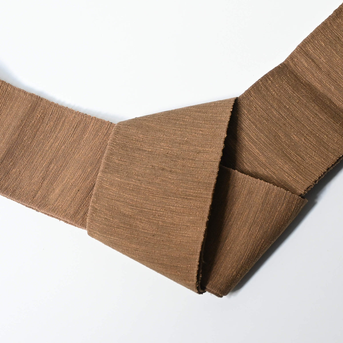 Close-up view of vintage men's tsumugi silk kaku obi, sash for kimono, in a warm brown tone.