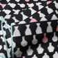 Close-up view of vintage Meisen silk kimono fabric piece, stylised vase motif in white and pink against black.