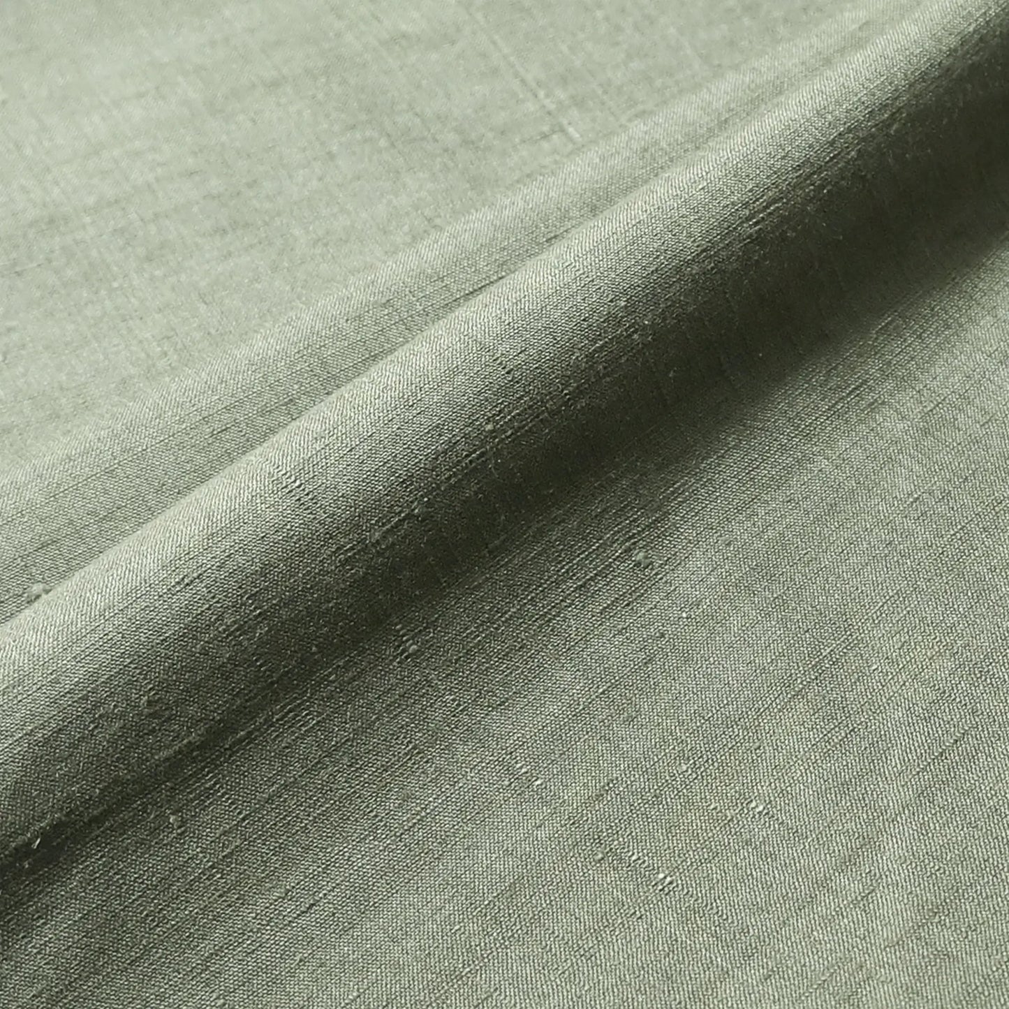 Close-up view of vintage plain tsumugi silk, men's kimono bolt in moss green, sold by the metre.