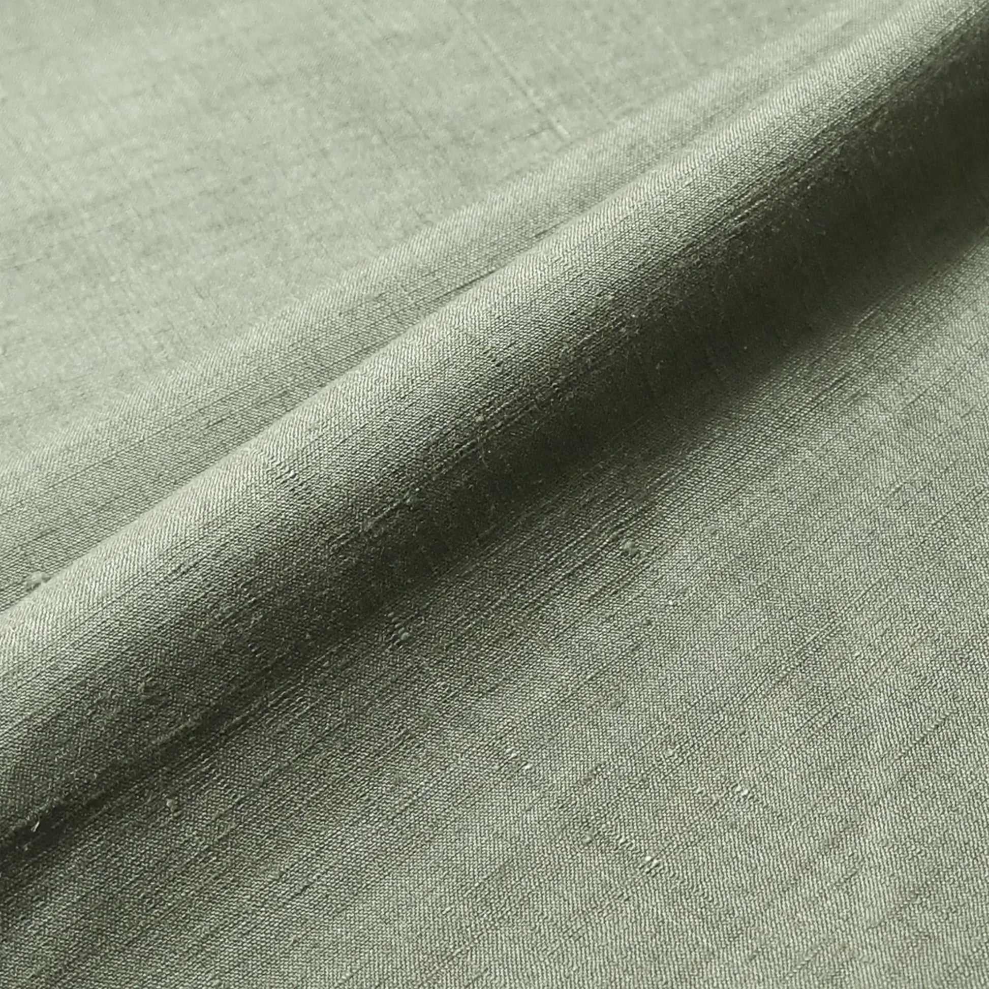 Close-up view of vintage plain tsumugi silk, men's kimono bolt in moss green, sold by the metre.