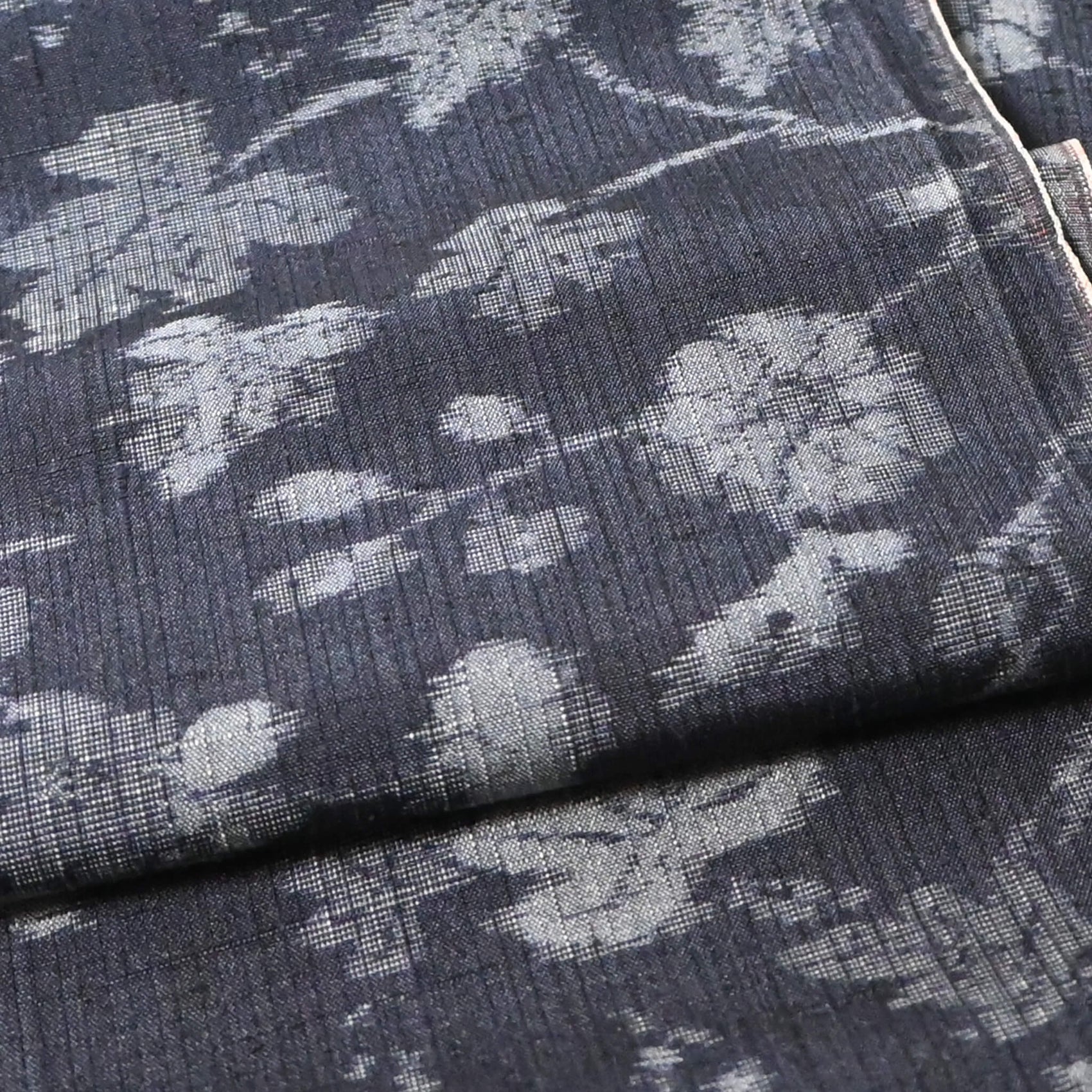 Close-up view of vintage tsumugi silk kimono fabric with silver grey vine floral pattern on a navy ground.