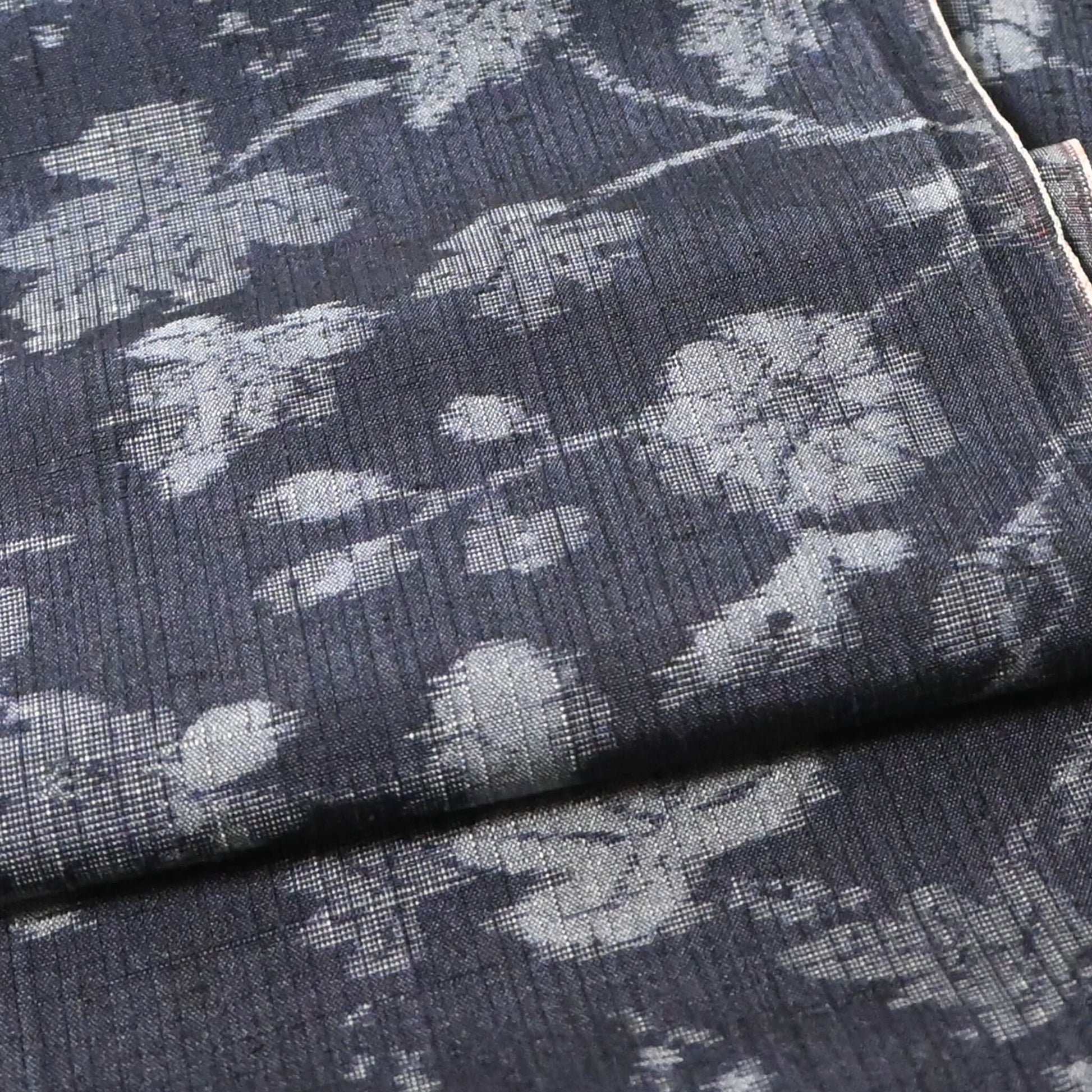 Close-up view of vintage tsumugi silk kimono fabric with silver grey vine floral pattern on a navy ground.