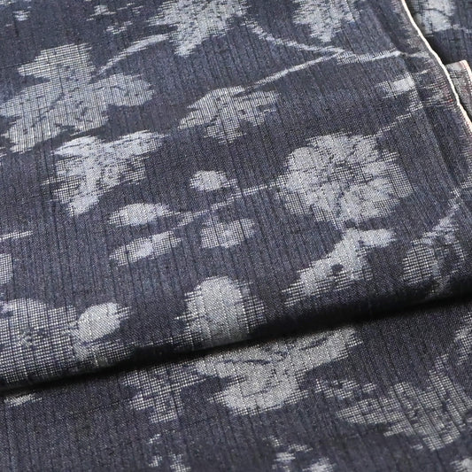 Close-up view of vintage tsumugi silk kimono fabric with silver grey vine floral pattern on a navy ground.