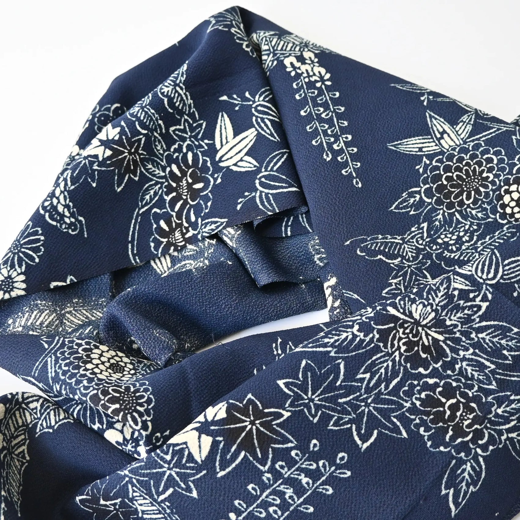 Detailed view of vintage Chirimen  silk crepe kimono fabric in navy with traditional Japanese seasonal flowers and trees.