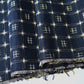 Close-up view of vintage navy tsumugi silk kimono fabric with woven kasuri pattern.