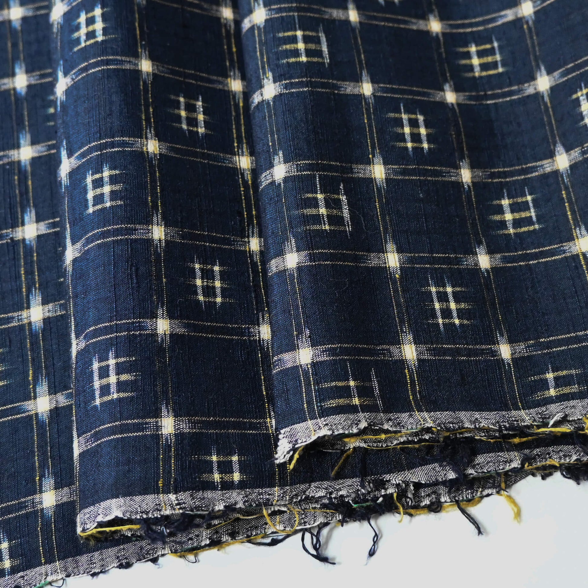 Close-up view of vintage navy tsumugi silk kimono fabric with woven kasuri pattern.