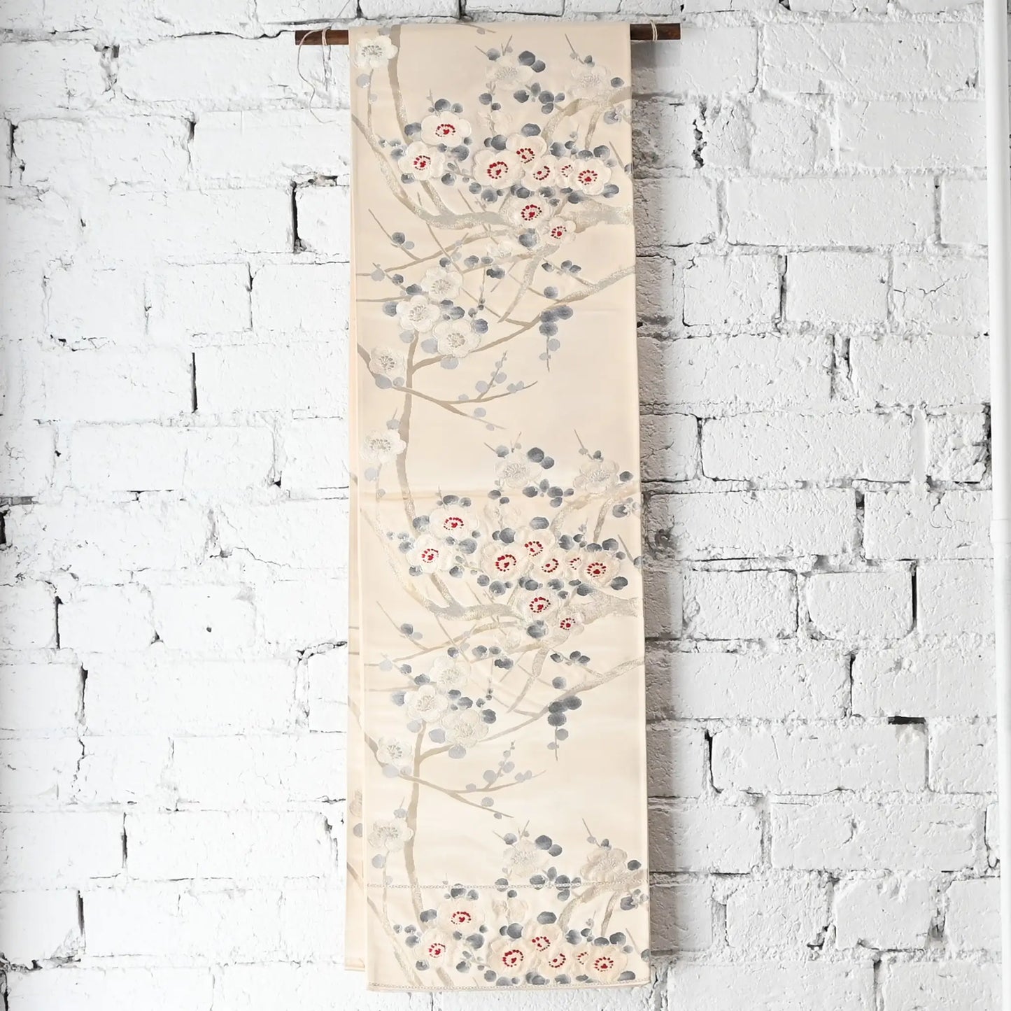 Hanging view of vintage women's off-white silk fukuro obi with elegant plum blossom motif.