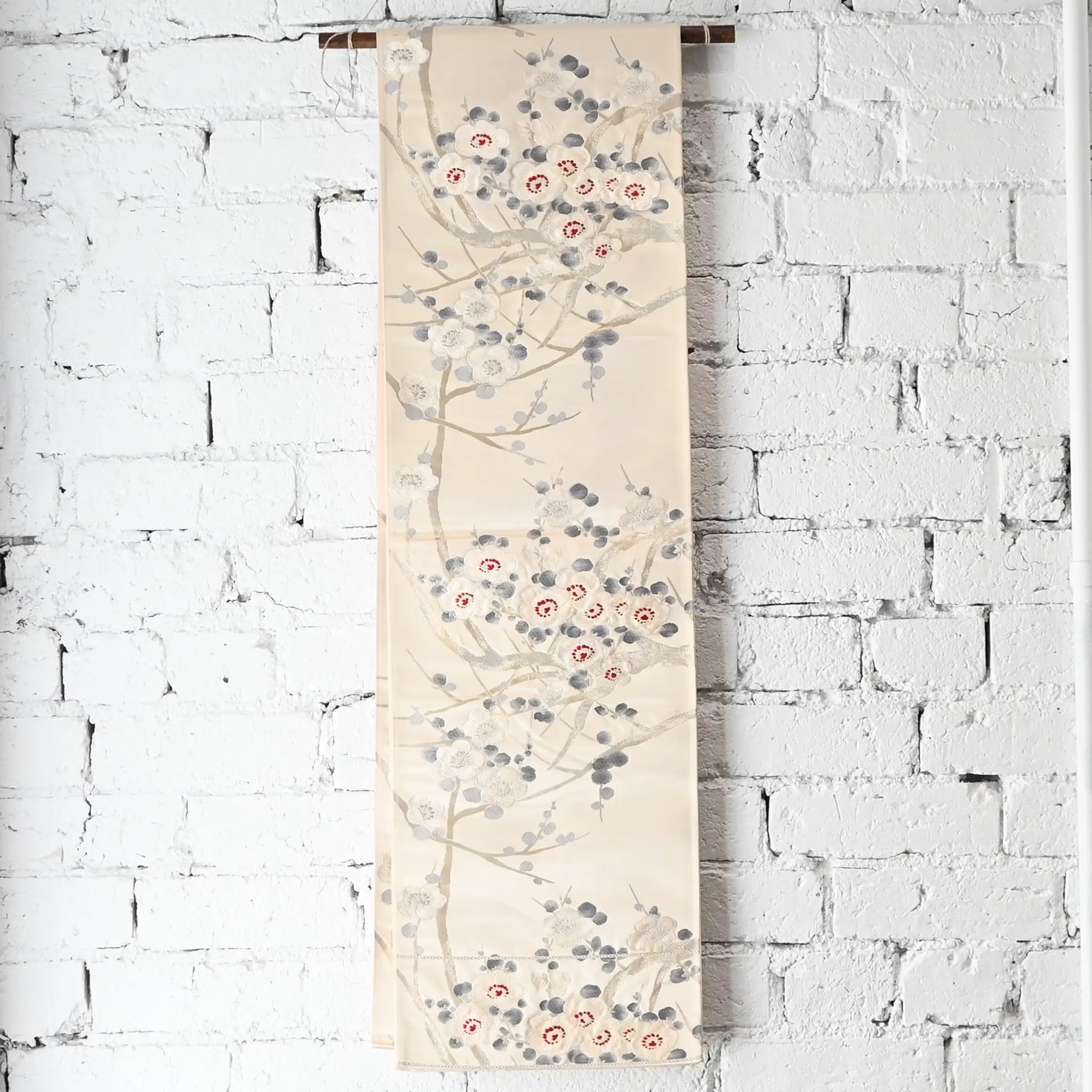 Hanging view of vintage women's off-white silk fukuro obi with elegant plum blossom motif.