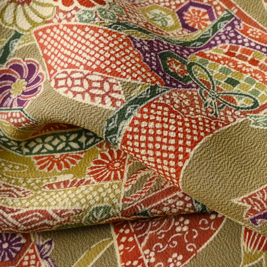 Detailed view of vintage olive green Chirimen silk crepe with auspicious motifs.