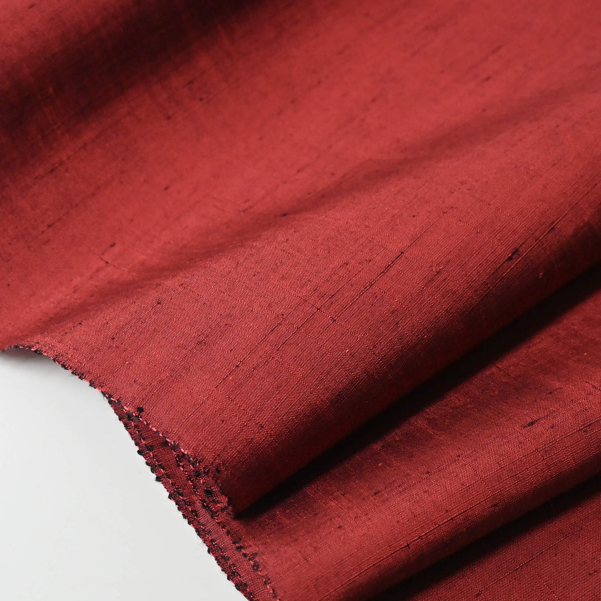 Cloes-up view of vintage plain tsumugi silk kimono fabric in brick red tone, sold by the metre.