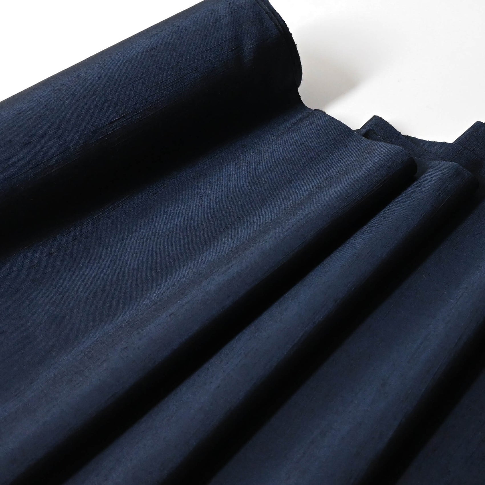 Close-up view of vintage plain tsumugi silk kimono fabric in deep blue sold by the metre.
