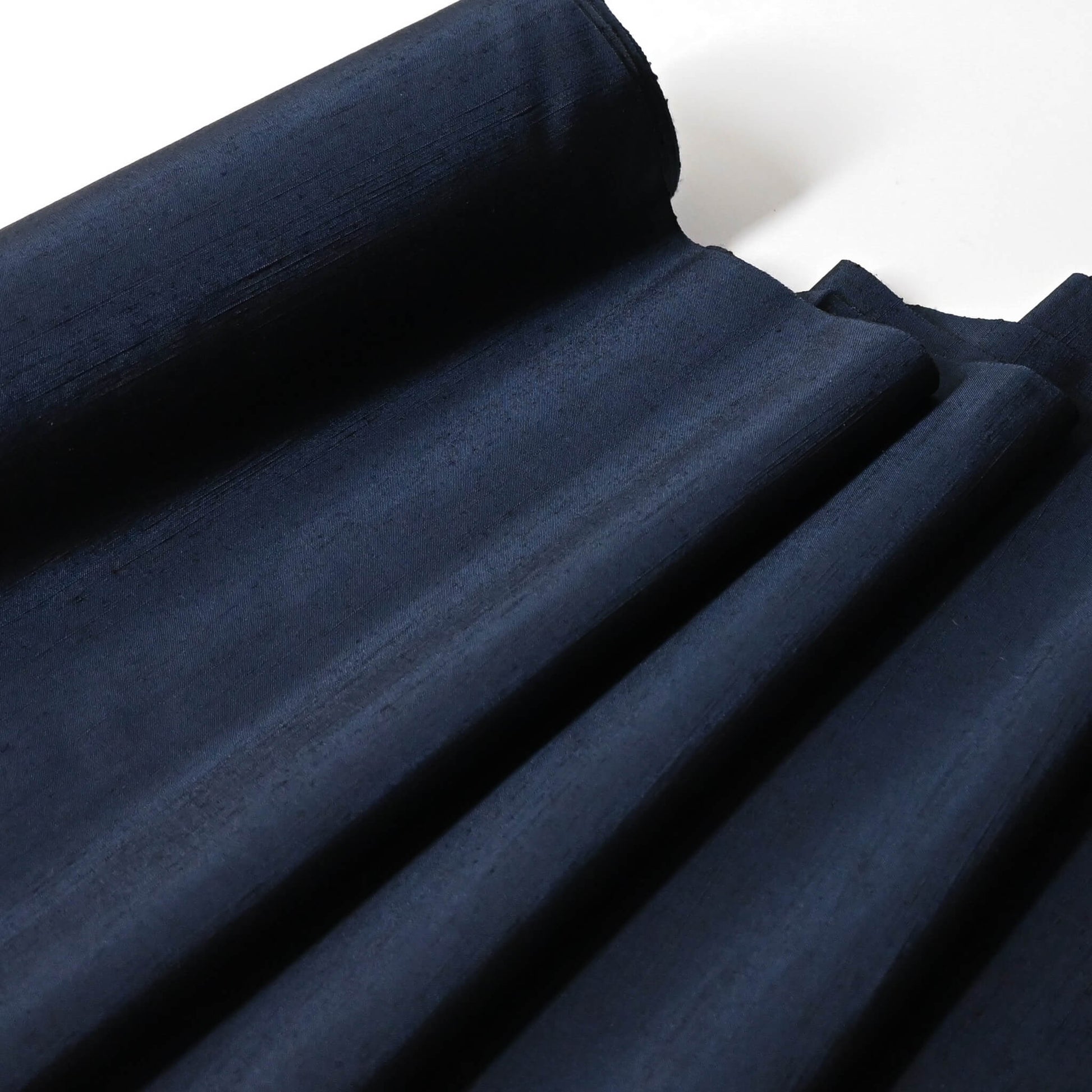 Close-up view of vintage plain tsumugi silk kimono fabric in deep blue sold by the metre.
