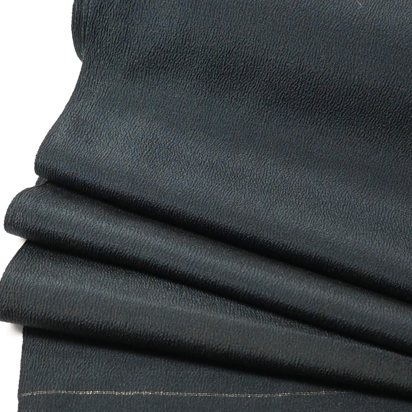close-up view of vintage plain silk crepe kimono fabric roll in deep green, sold by the metre.
