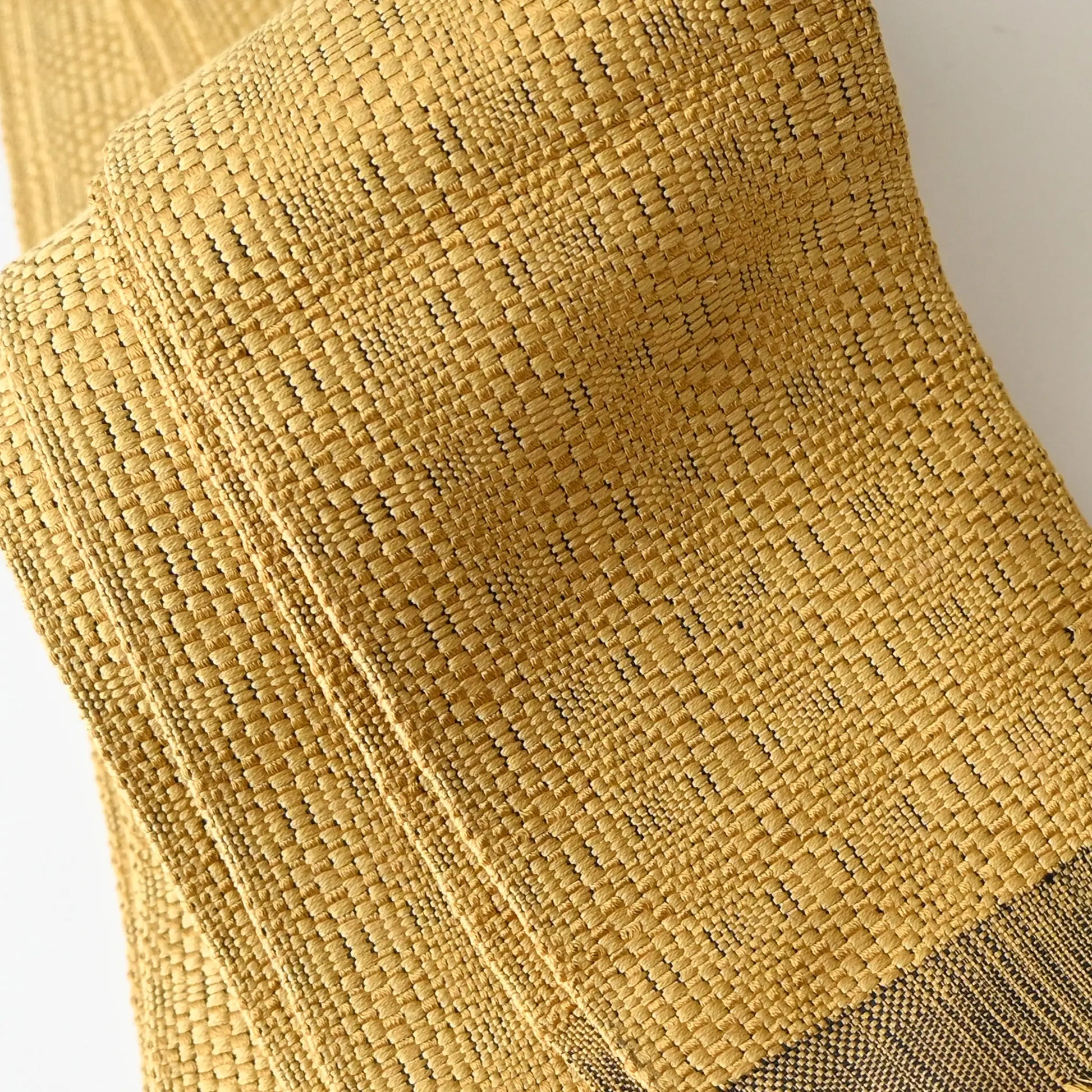 Close-up view of vintage Japanese men's silk Kaku Obi with woven design in soft yellow.