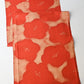Full view of vintage Japanese tsumugi silk kimono fabric piece in reddish orange with bold plum blossom.