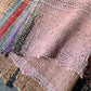 Close-up view of vintage Sakiori fragment cloth from Tohoku region, woven from shredded strips of recycled kimono and futon covers.
