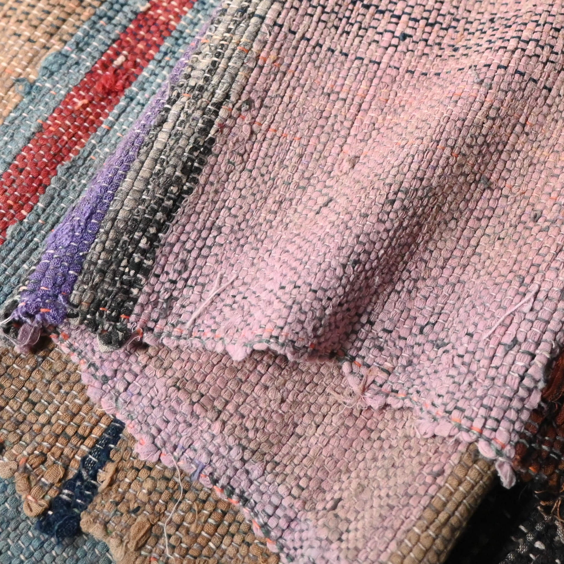 Close-up view of vintage Sakiori fragment cloth from Tohoku region, woven from shredded strips of recycled kimono and futon covers.
